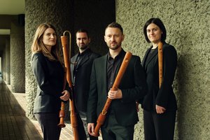 The Flautadors tighter composition holding instruments near a concrete wall